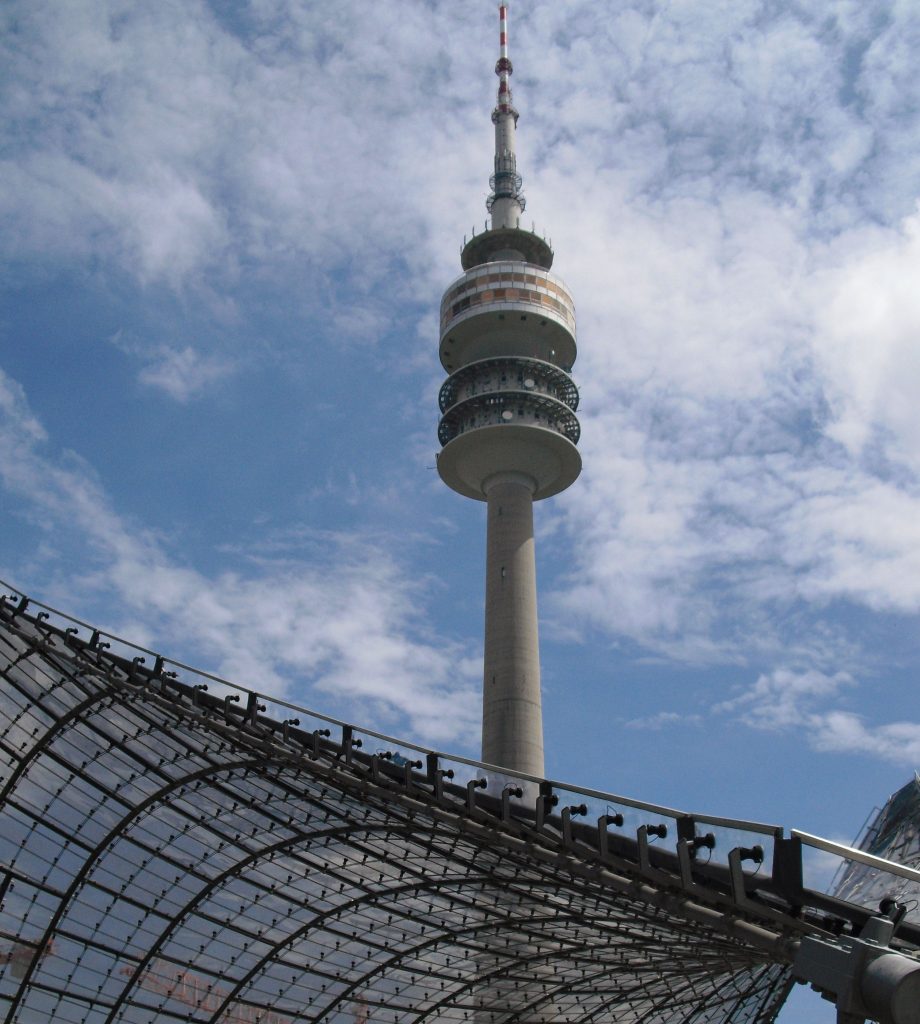Der Olympiaturm hinter dem Dach des Olympiaparks in München. Foto: Niklas Brose